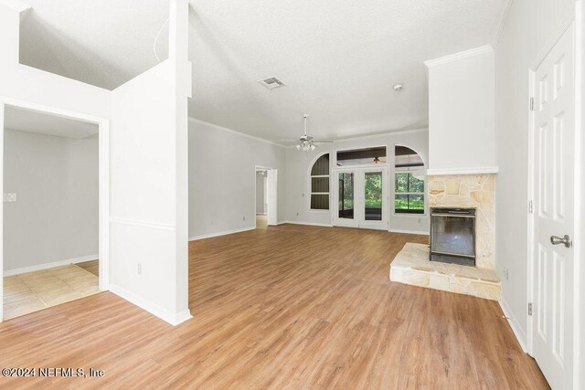 unfurnished living room with a stone fireplace, light hardwood / wood-style floors, crown molding, and ceiling fan