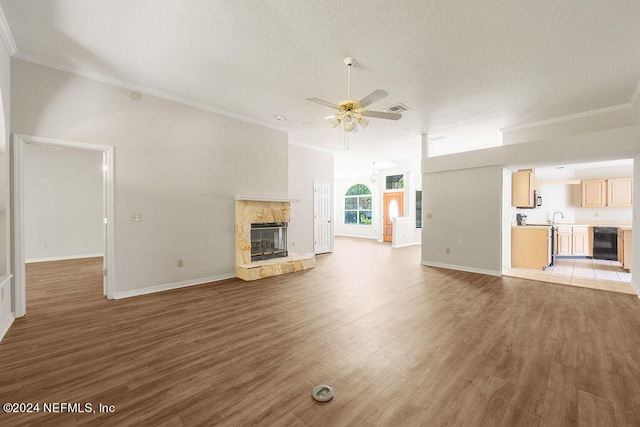 unfurnished living room featuring light tile patterned floors, a textured ceiling, ceiling fan, a fireplace, and ornamental molding