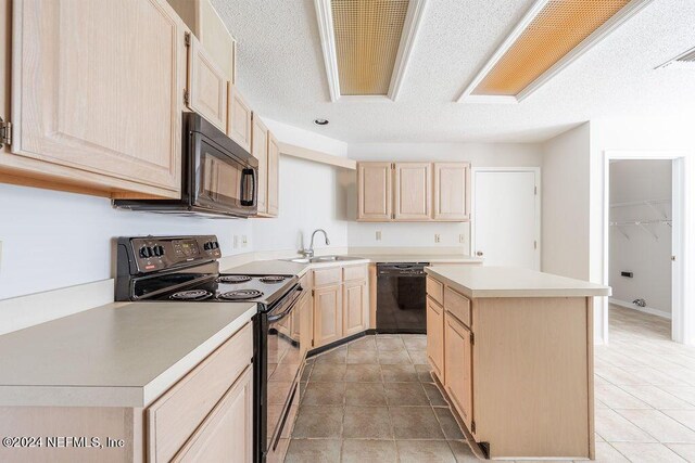 kitchen with black appliances, light brown cabinets, sink, a center island, and light tile patterned floors