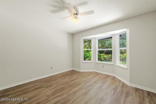 empty room with a textured ceiling, ceiling fan, and wood-type flooring