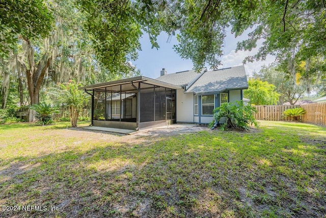 back of property featuring a sunroom, a fenced backyard, a yard, and a chimney