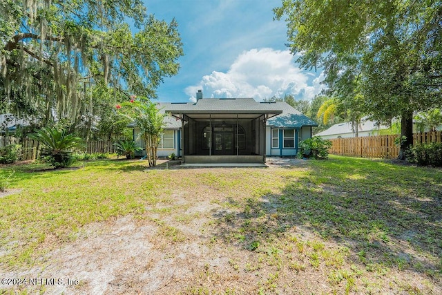 back of house with a yard, a chimney, a fenced backyard, and a sunroom