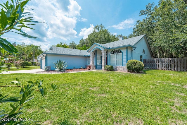 view of front facade featuring a garage, driveway, brick siding, fence, and a front yard