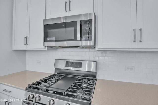 kitchen with decorative backsplash, white cabinets, and appliances with stainless steel finishes