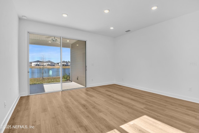 unfurnished room with light hardwood / wood-style flooring and a water view