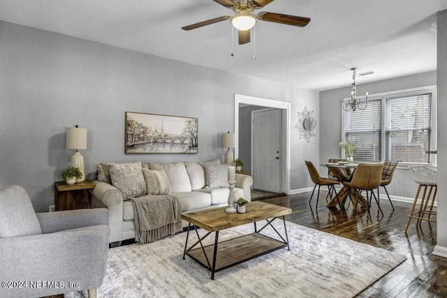 living room with wood-type flooring, visible vents, baseboards, and ceiling fan with notable chandelier