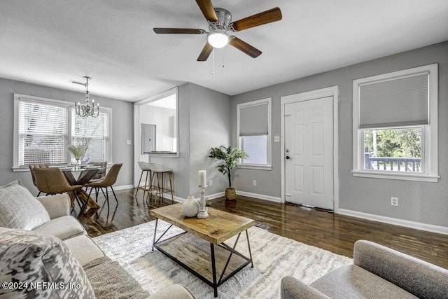 living area featuring ceiling fan with notable chandelier, plenty of natural light, baseboards, and wood finished floors