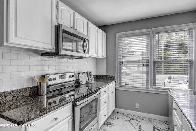 kitchen featuring appliances with stainless steel finishes, decorative backsplash, white cabinets, and baseboards