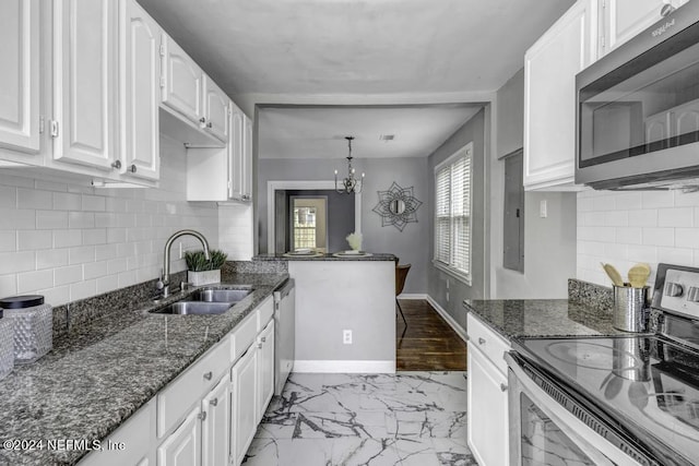 kitchen featuring baseboards, dark stone counters, stainless steel appliances, white cabinetry, and a sink