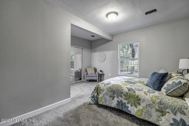 carpeted bedroom featuring visible vents, a textured ceiling, and baseboards