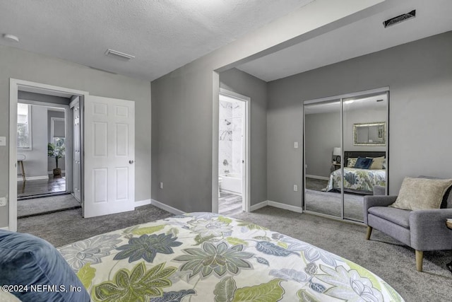 carpeted bedroom featuring a textured ceiling, visible vents, baseboards, a closet, and ensuite bath