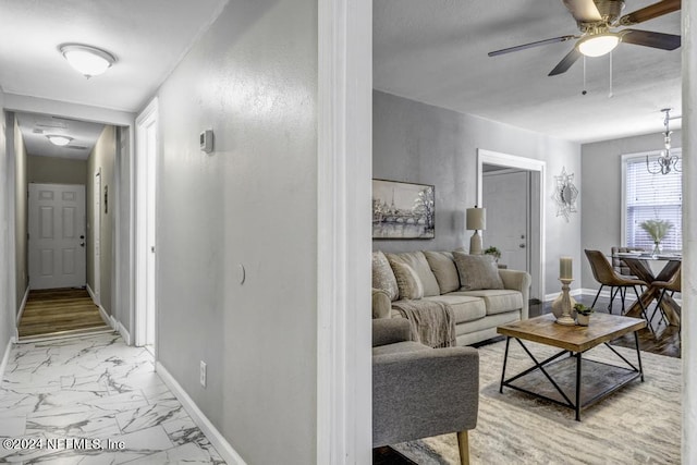 living room with marble finish floor, ceiling fan, and baseboards