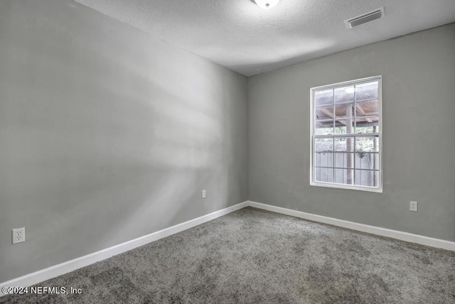 carpeted empty room featuring visible vents, a textured ceiling, and baseboards