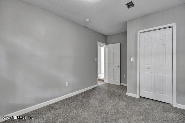 unfurnished bedroom featuring carpet floors, a textured ceiling, baseboards, and a closet