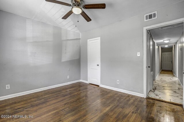 unfurnished bedroom with baseboards, vaulted ceiling, visible vents, and wood-type flooring