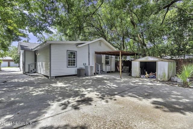 exterior space with central AC unit, entry steps, a carport, an outdoor structure, and driveway