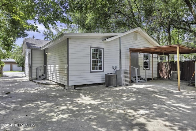 view of side of property featuring entry steps, cooling unit, fence, and driveway