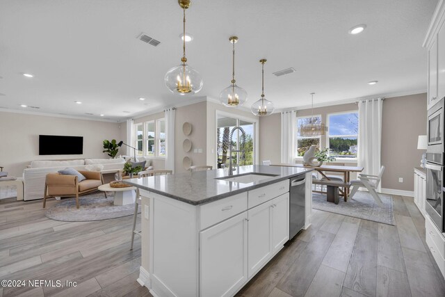 kitchen featuring a kitchen island with sink, sink, crown molding, and light hardwood / wood-style flooring