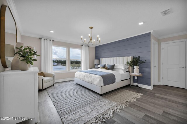 bedroom featuring wood-type flooring, ornamental molding, and an inviting chandelier