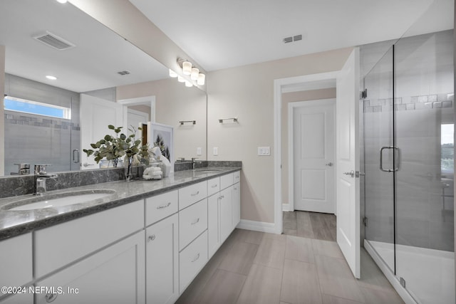 bathroom with tile patterned floors, dual vanity, and a shower with shower door