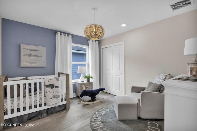 bedroom with light hardwood / wood-style flooring, a nursery area, and a closet