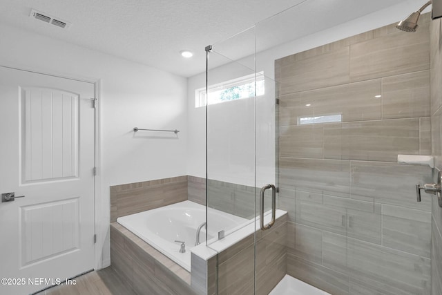 bathroom with a shower stall, a garden tub, visible vents, and a textured ceiling