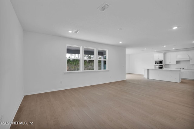 unfurnished living room featuring recessed lighting, visible vents, light wood finished floors, and baseboards