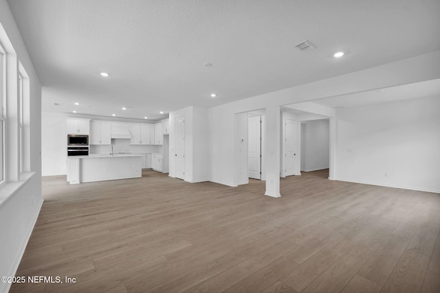 unfurnished living room with recessed lighting, visible vents, baseboards, and light wood finished floors