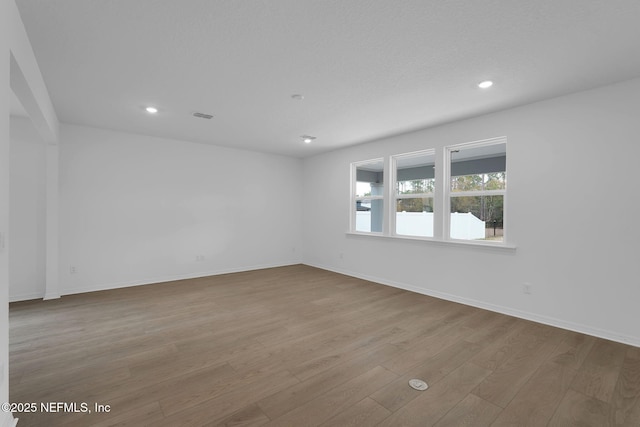 empty room with recessed lighting, visible vents, baseboards, and wood finished floors