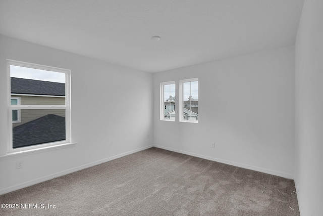 carpeted spare room featuring baseboards