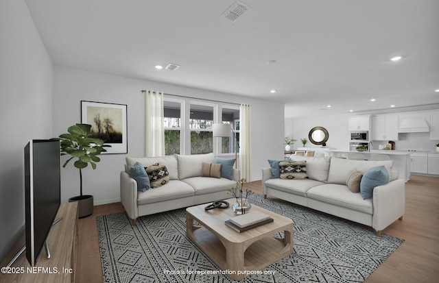 living area featuring light wood-style flooring, recessed lighting, visible vents, and baseboards