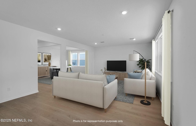 living room featuring recessed lighting, baseboards, and light wood-style flooring