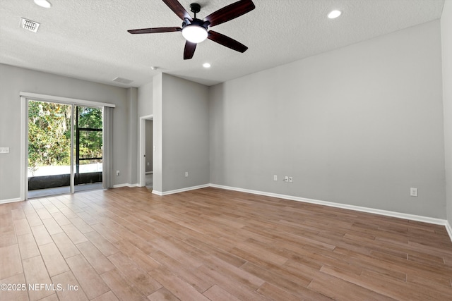 empty room with ceiling fan, a textured ceiling, and light wood-type flooring