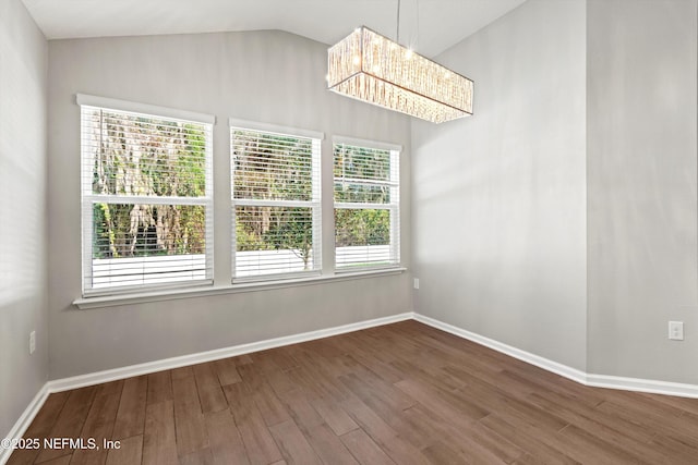 unfurnished dining area featuring hardwood / wood-style flooring, vaulted ceiling, and a notable chandelier