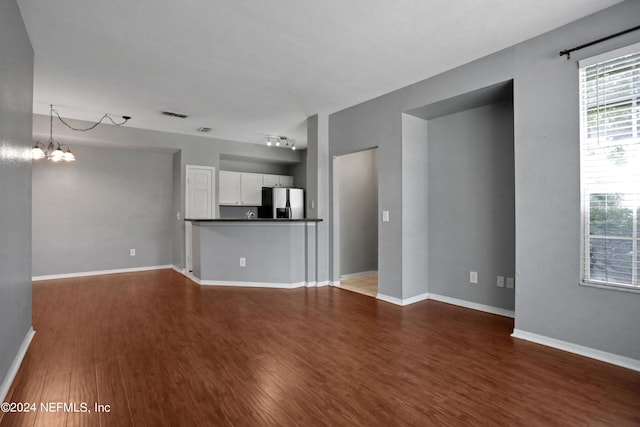 unfurnished living room featuring wood-type flooring and a notable chandelier