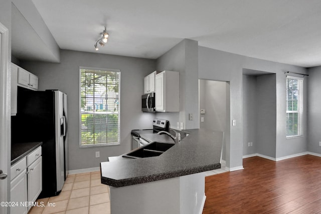 kitchen with white cabinetry, stainless steel appliances, kitchen peninsula, and a healthy amount of sunlight