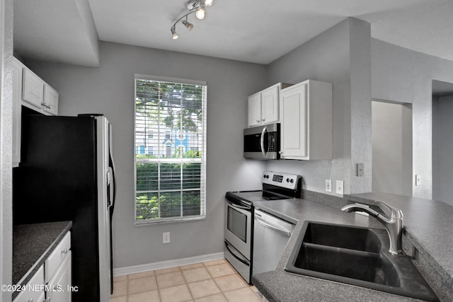 kitchen with light tile patterned floors, stainless steel appliances, sink, and white cabinets