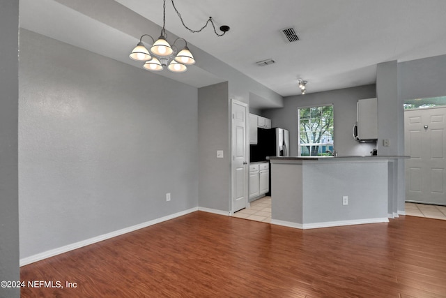 kitchen featuring stainless steel refrigerator with ice dispenser, white cabinets, light hardwood / wood-style floors, and kitchen peninsula