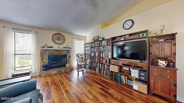 living room featuring lofted ceiling, wood-type flooring, a fireplace, and a textured ceiling