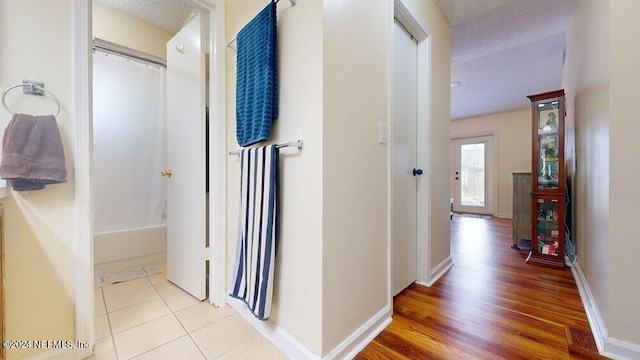 corridor with a textured ceiling and light tile patterned flooring