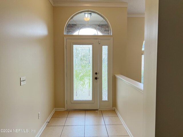 foyer entrance featuring ornamental molding, light tile patterned flooring, and a wealth of natural light