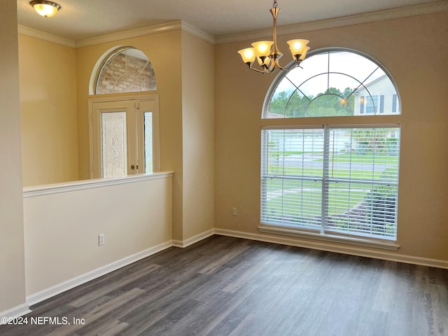 spare room with dark wood-type flooring, crown molding, and a chandelier