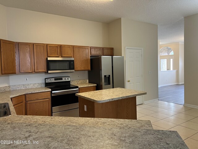 kitchen with a textured ceiling, stainless steel appliances, and light hardwood / wood-style floors