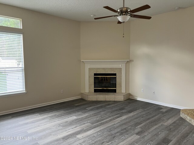 unfurnished living room featuring ceiling fan, a fireplace, a textured ceiling, and hardwood / wood-style flooring