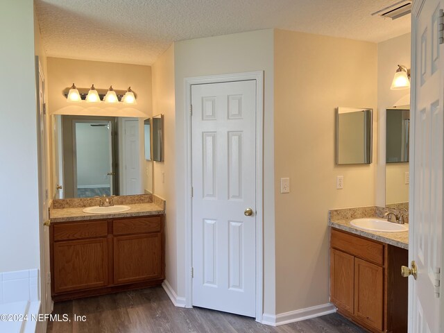 bathroom with a bathing tub, hardwood / wood-style floors, and a textured ceiling