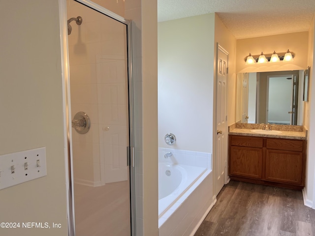 bathroom with hardwood / wood-style flooring, plus walk in shower, vanity, and a textured ceiling