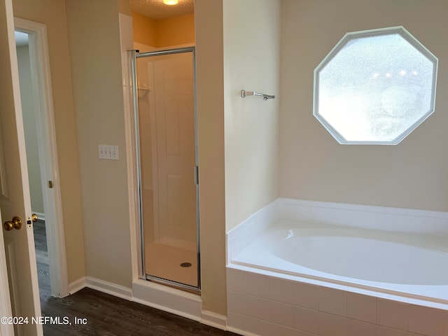 bathroom with shower with separate bathtub and wood-type flooring