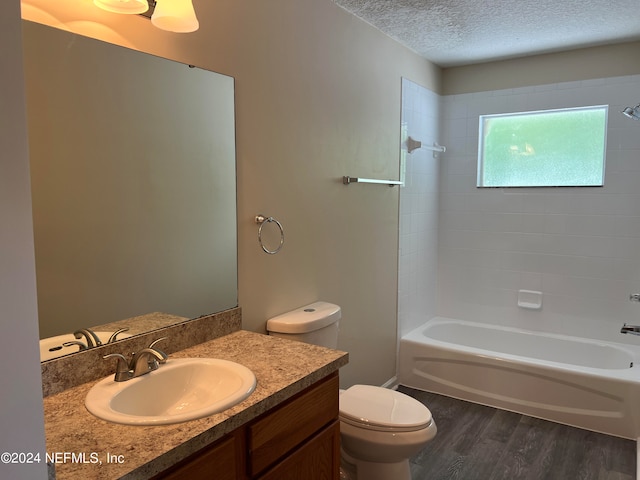 full bathroom with washtub / shower combination, a textured ceiling, toilet, vanity, and wood-type flooring