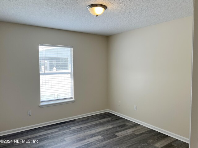 empty room with a textured ceiling, hardwood / wood-style flooring, and a healthy amount of sunlight