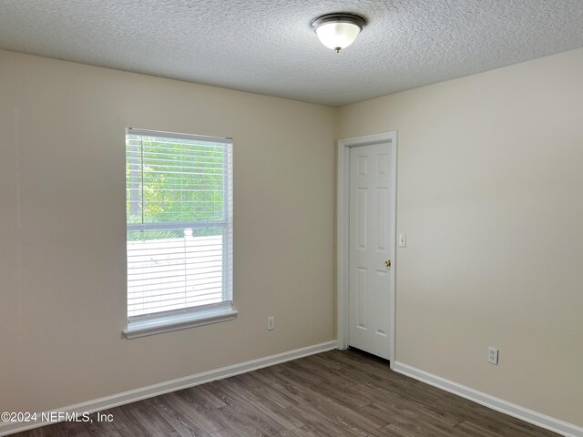 spare room with a textured ceiling and wood-type flooring